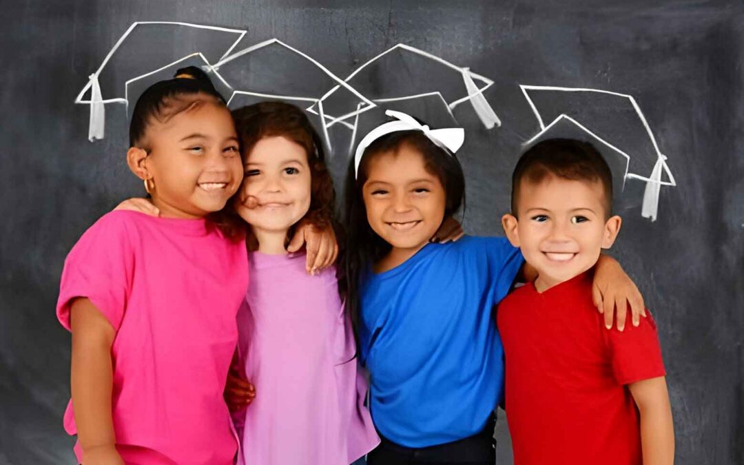 Four children in graduation hats stand proudly in front of a blackboard, celebrating their achievements in the best preschool near McKinney.